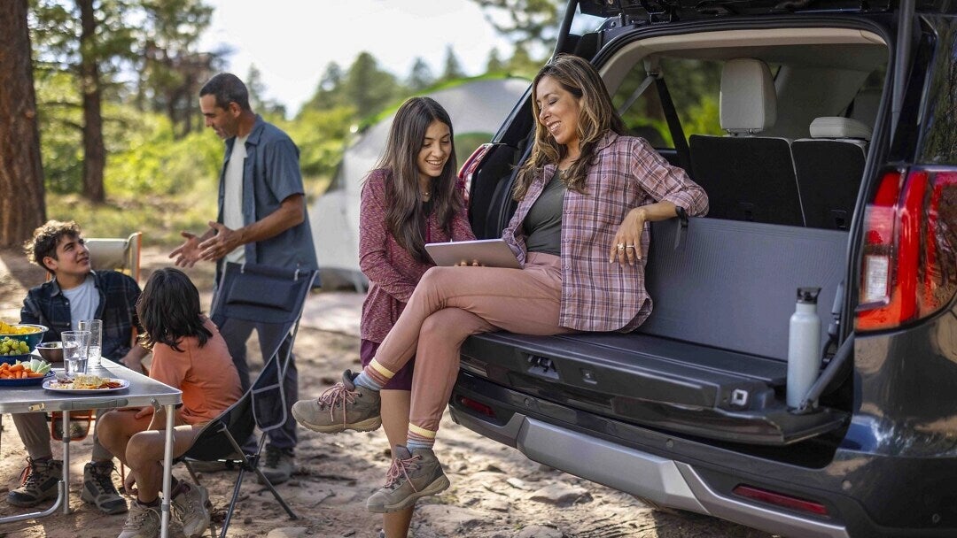 a woman sitting on the 'tailgate' of a 2025 ford expedition