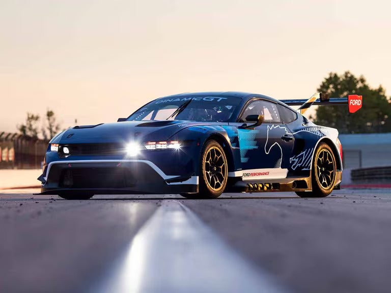 a ford mustang gt3 racecar parked on a racetrack at dusk