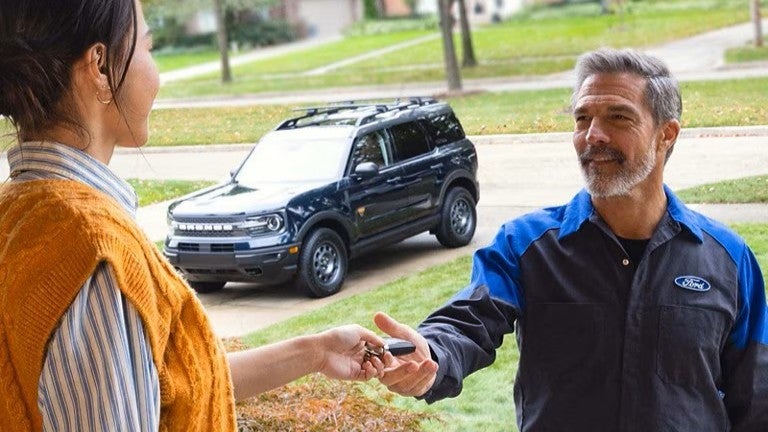 a ford technician picking up a ford vehicle from an owners home